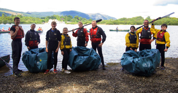 Happy family, wearing wetsuits, standing with homemade corracles, by Derwent Water 